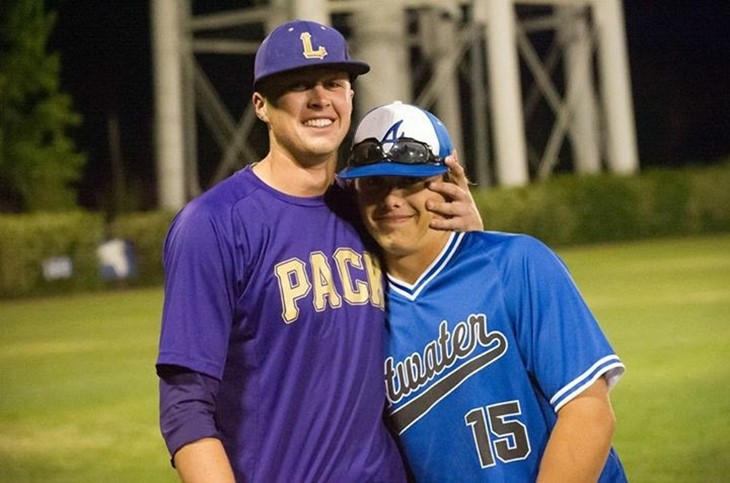 Two baseball players posing for a picture on a field.